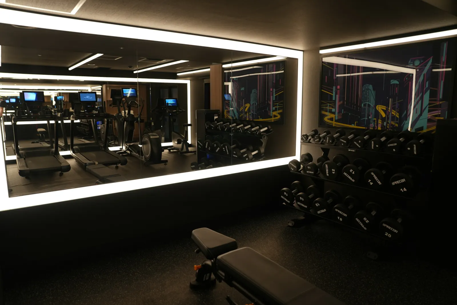 Phòng gym khách sạn có máy chạy bộ, giàn tạ và gương lớn