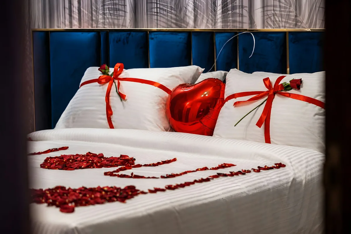 Giường Phòng Tân Hôn trang trí ruy băng đỏ, bóng bay trái tim và cánh hoa hồng